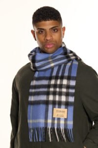 A folded red and grey tartan cashmere scarf on a wooden surface.