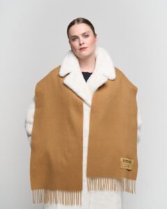 A professional styling shot of an oversized cashmere stole worn as a wrap, perfect for international festival travel.