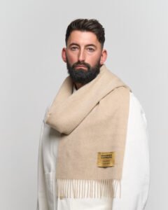 A folded light brown cashmere scarf in a luxury signature box.